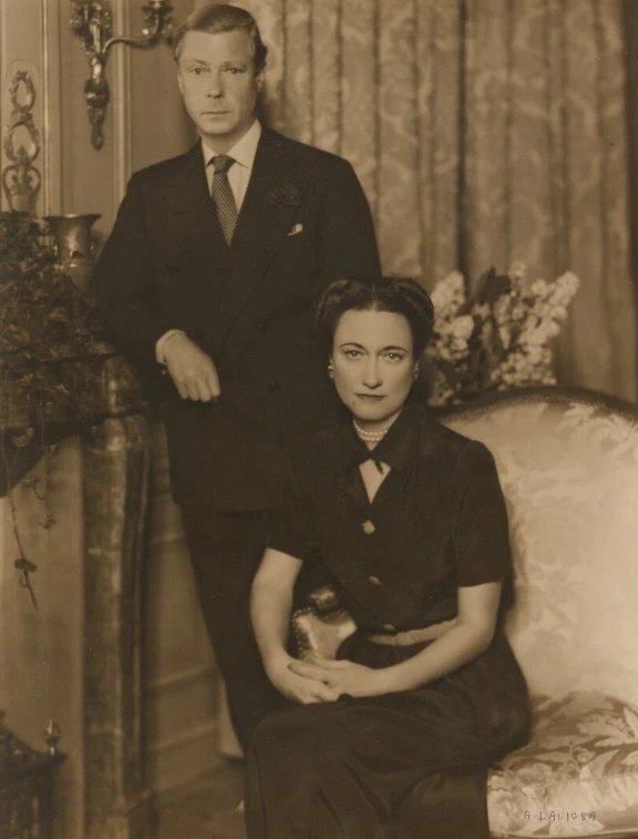 Black-and-white portrait of the Duke of Windsor standing behind the seated Duchess of Windsor in a drawing room