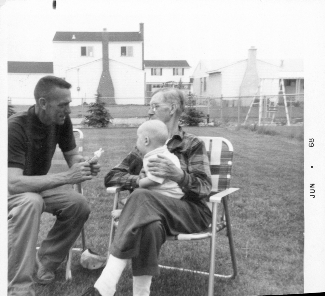 Two men in lawn chairs, the older one holding a baby